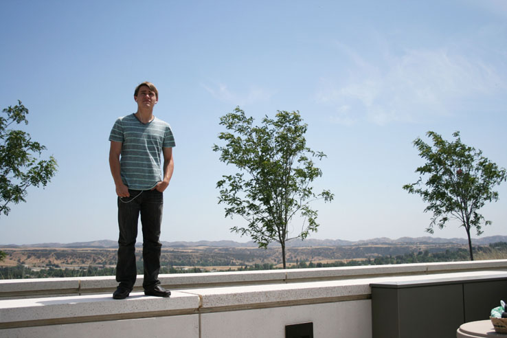 A student standing in front of a few small trees.